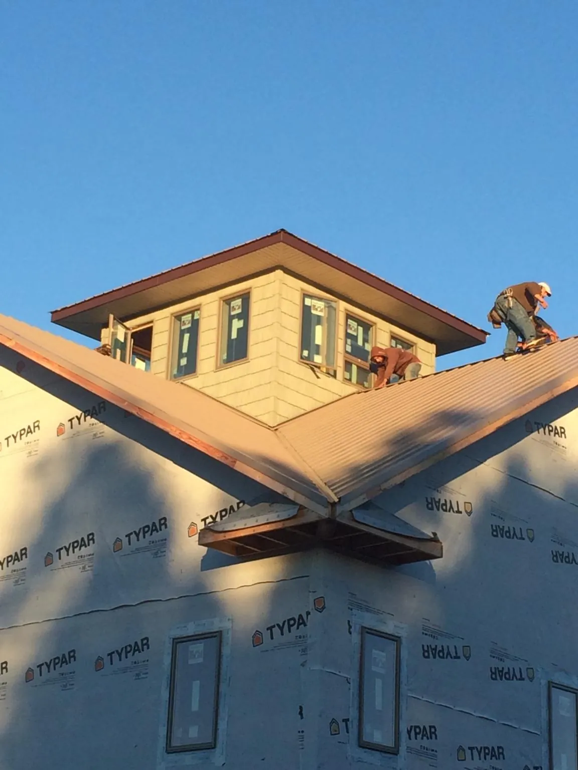 Roofers working around a rooftop cupola on a new metal roof at sunset — Roof Waterproofing in Woodland by Roofing Brothers